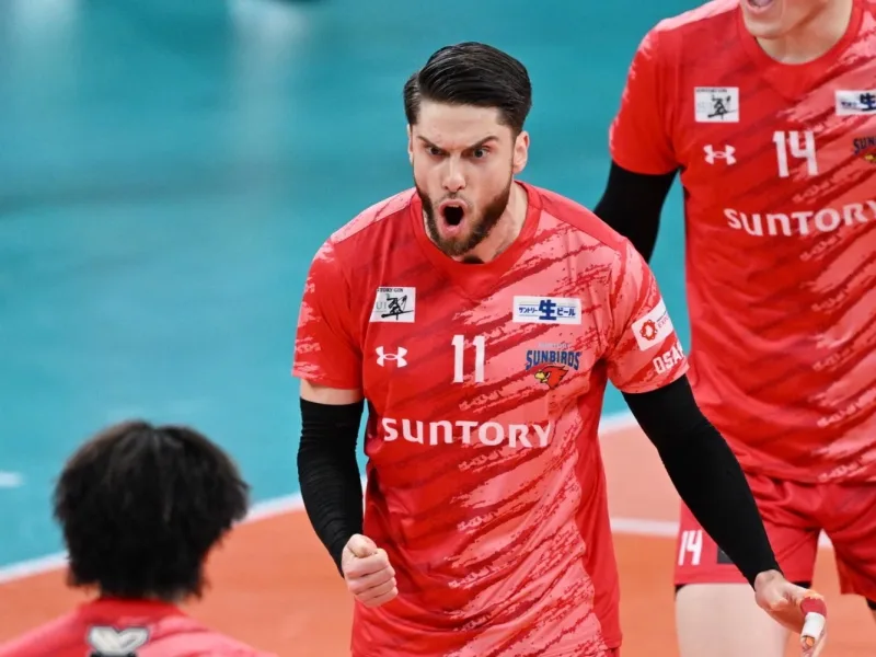 Aleksander Śliwka celebrates in a red Suntory Sunbirds volleyball jersey.