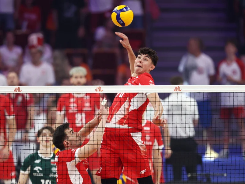 Jakub Nowak attacks above the net for Poland during international volleyball.